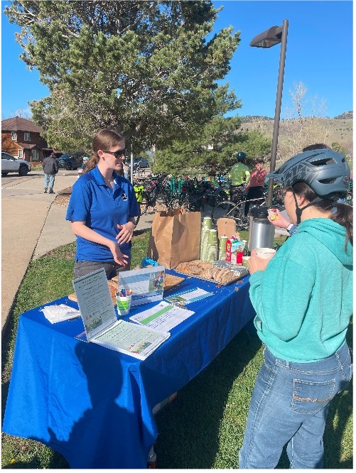 City of Boulder employee standing behind desk outside showing patrons informational material