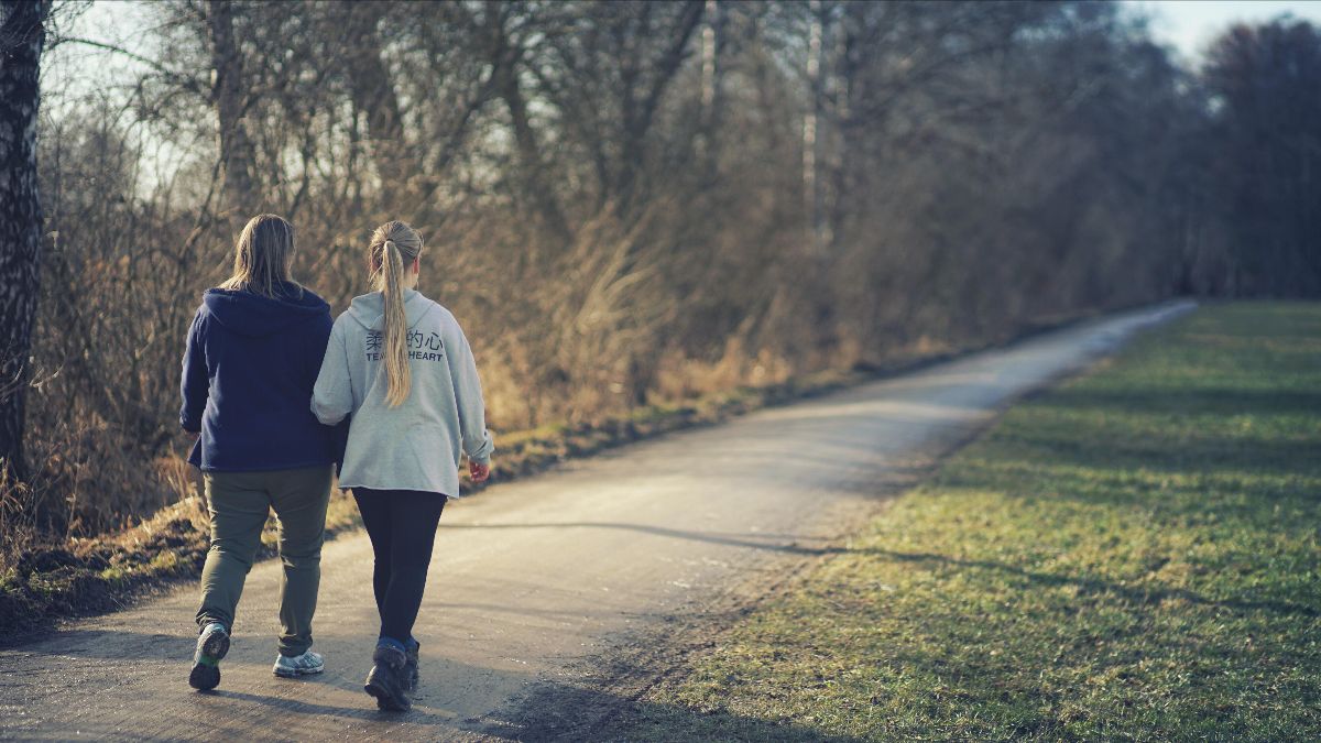 two teenage girls walking on path in a park