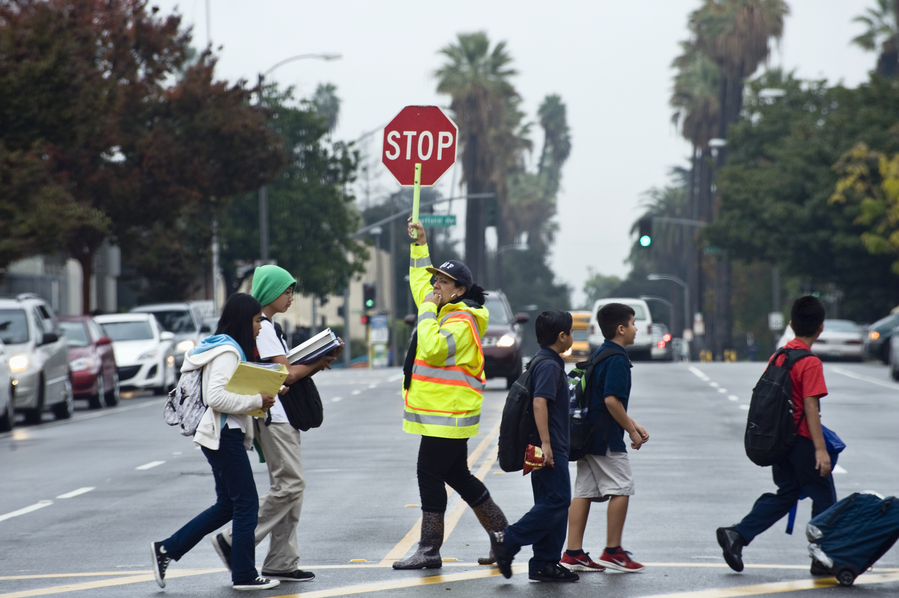children crossing at crosswalk with guard holding stop sign