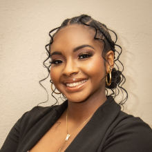 Girl with dark hair and dark suit jacket smiling in a professional headshot