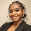Girl with dark hair and dark suit jacket smiling in a professional headshot