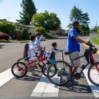 male with bike walking students with bikes across crosswalk