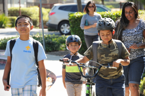 kids walking with adult on sidewalk